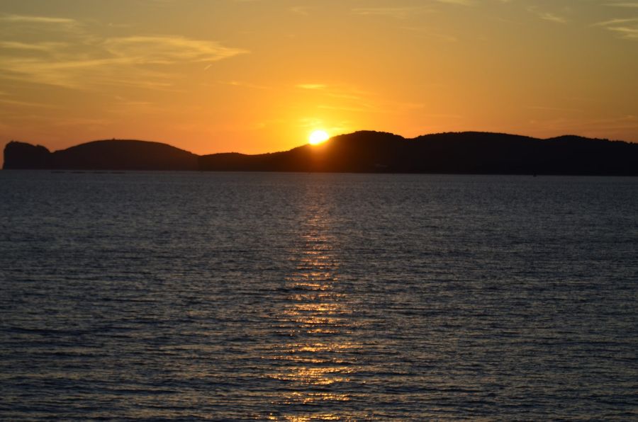 Sunset over the sea behind a dark headland